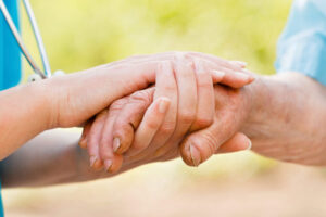 A Bethany Home's nurse holding a resident's hand.